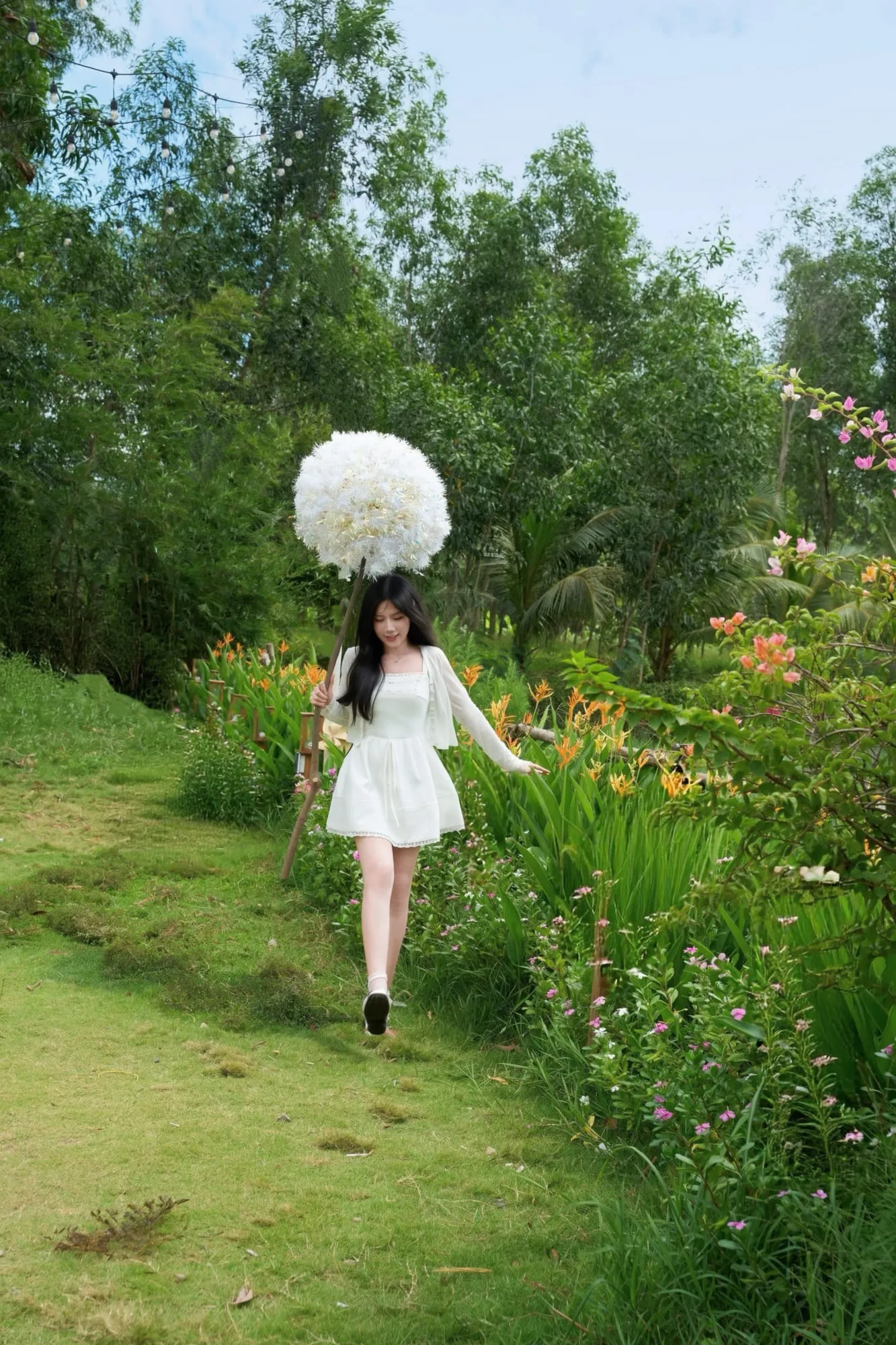 Khách thương váy trắng bước qua lối hoa cùng quả cầu bồ công anh