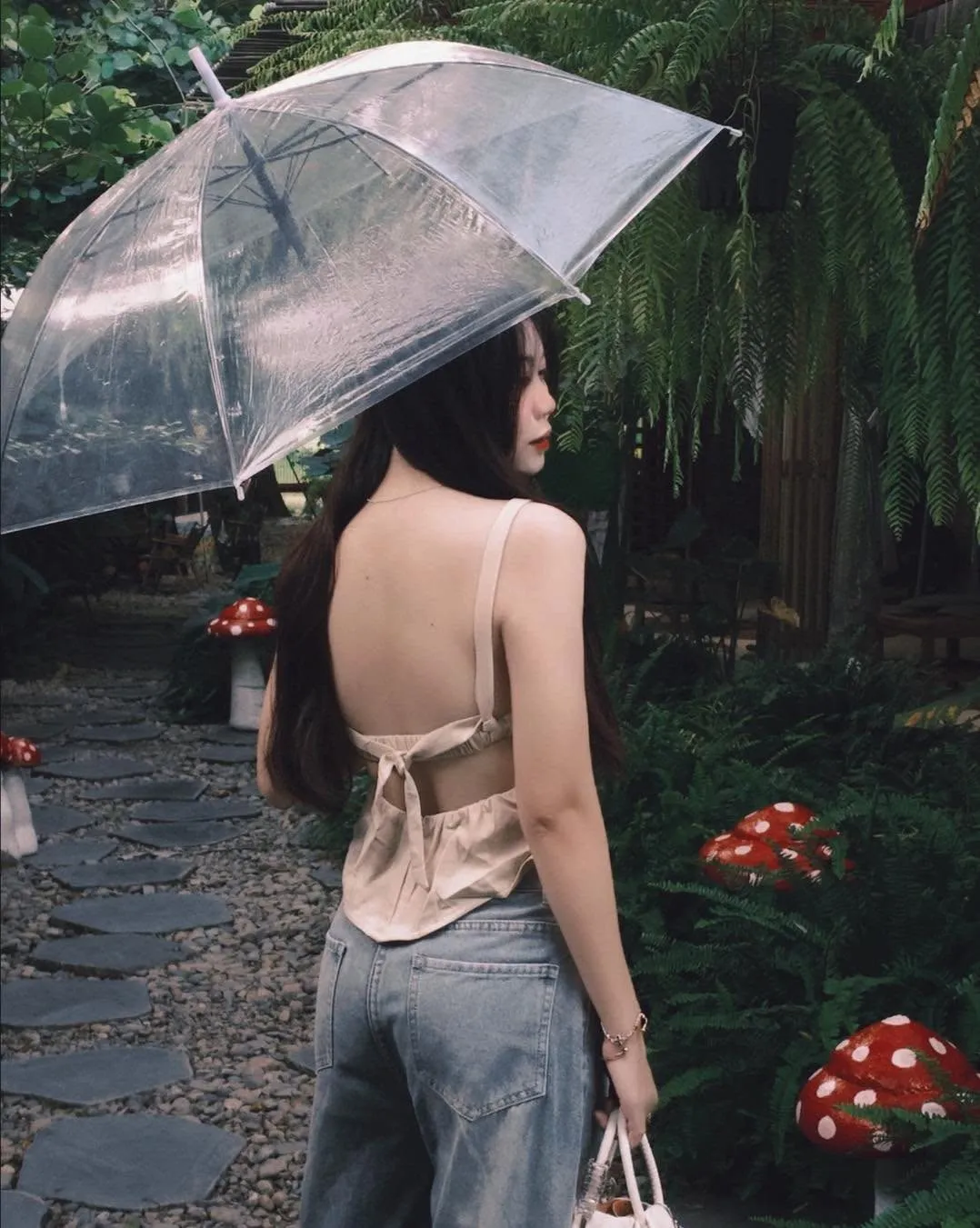 Khách thương cầm ô trong suốt bước qua lối vườn nấm sau mưa
